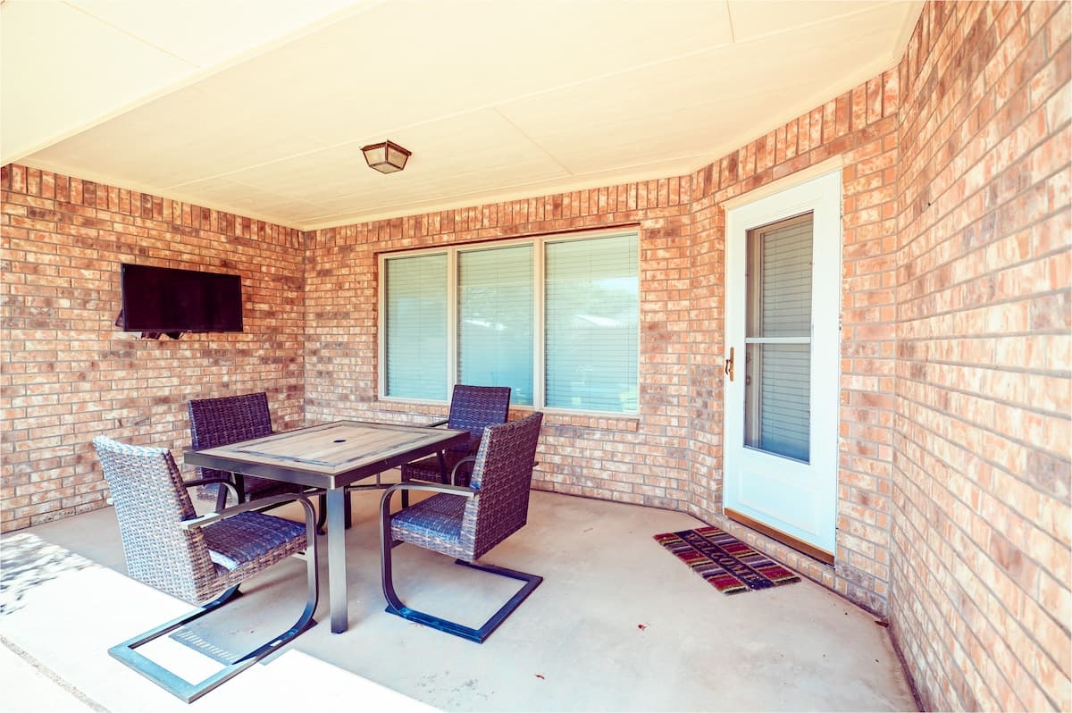 Covered patio with seating for four people and an outdoor TV.